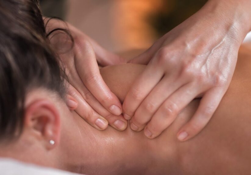 Close up image of physiotherapist massaging female patient with injured neck muscle. Sports injury treatment