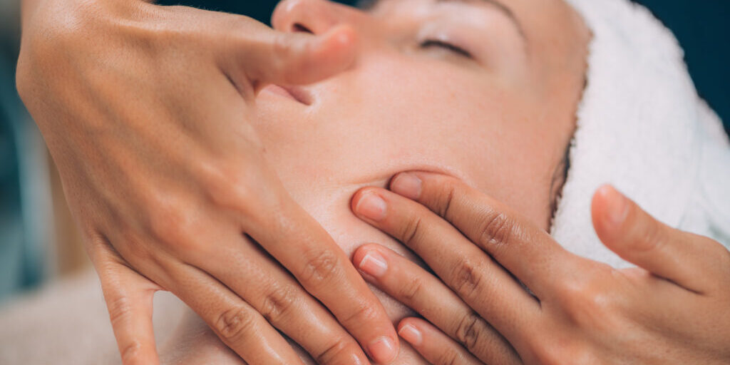 Face Fitness. Beautiful woman receiving face lifting massage in beauty salon.